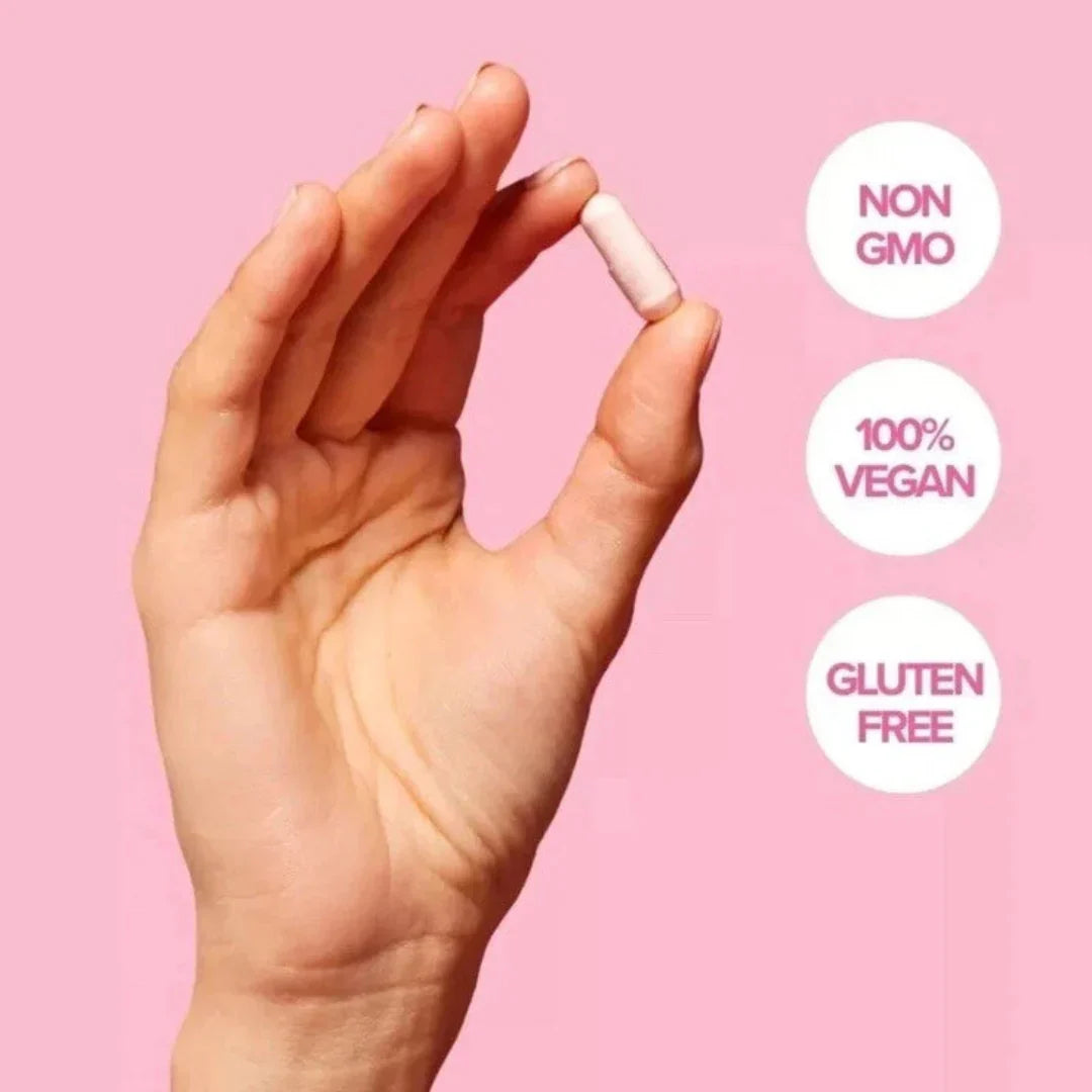 Hand holding a pill with 'Non GMO', '100% Vegan', and 'Gluten Free' labels on a pink background